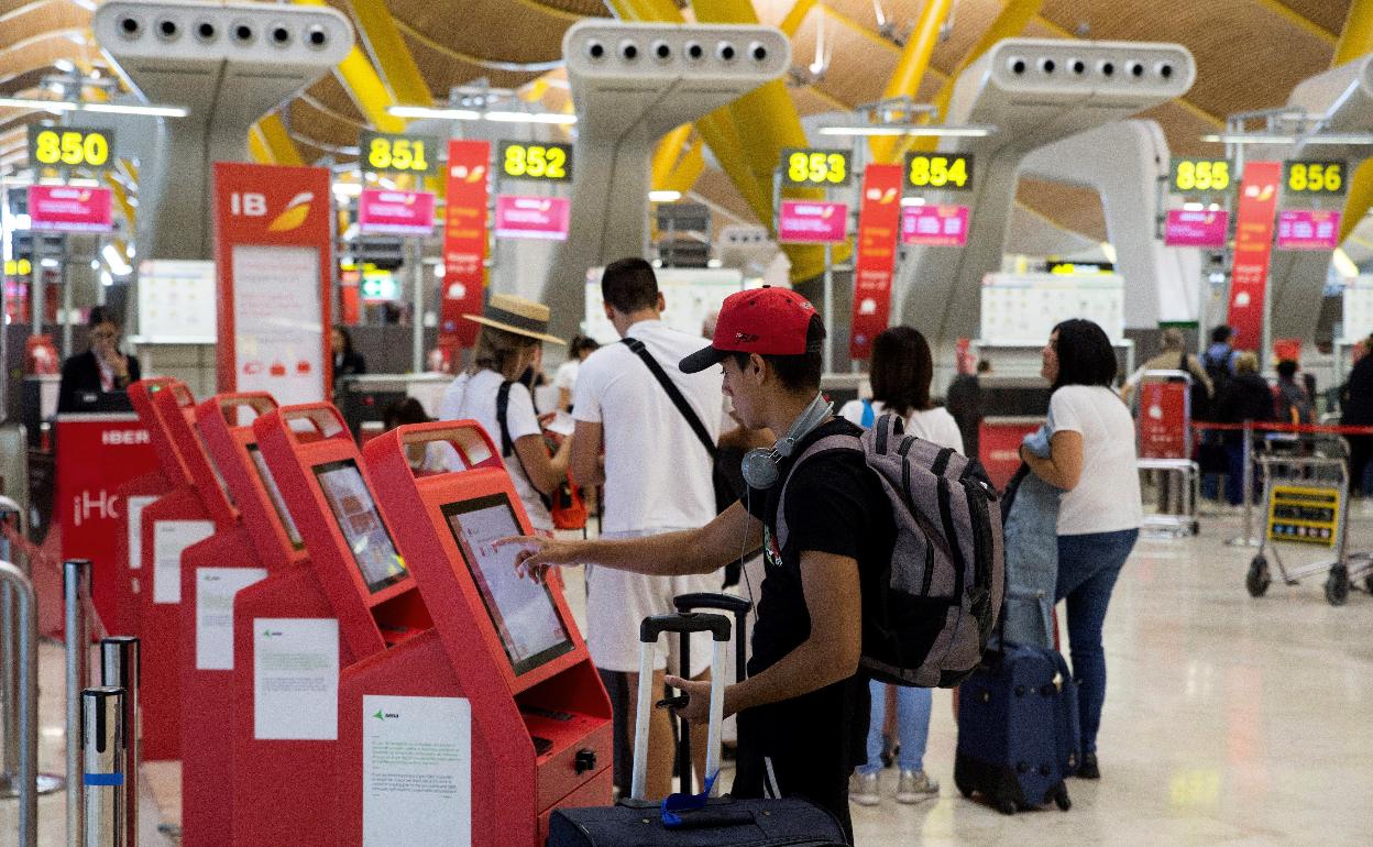 Varios viajeros utilizan las máquinas de facturación electrónica en el aeropuerto madrileño de Barajas. 