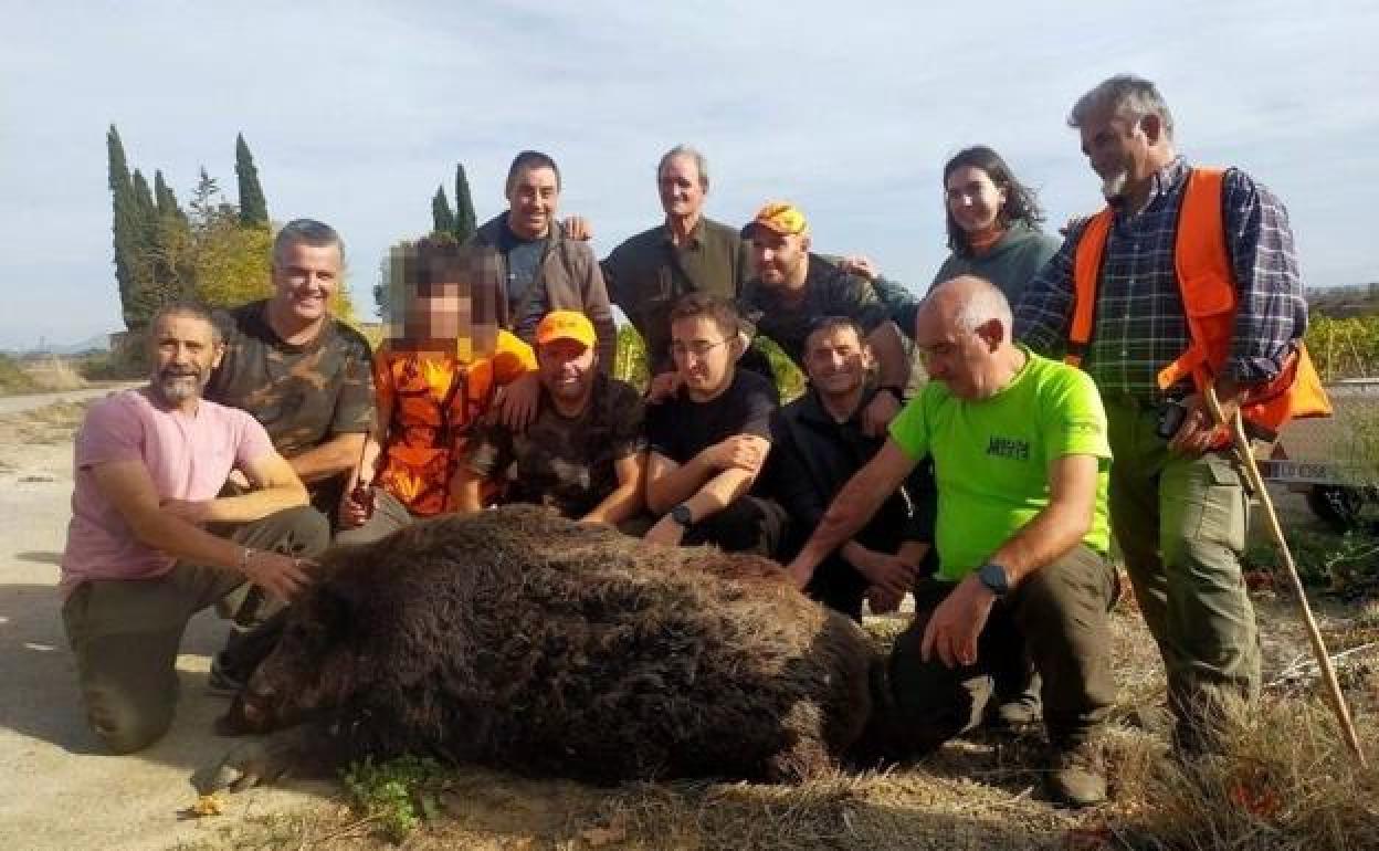 El grupo de cazadores posa con el jabalí abatido. 