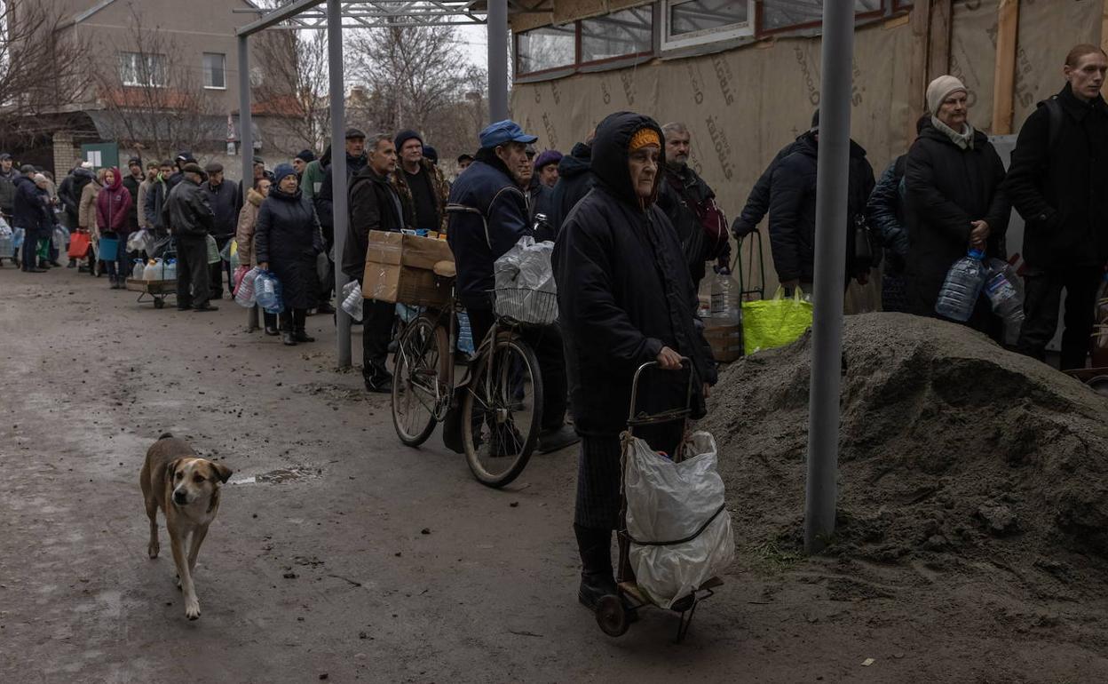 Decenas de ciudadanos guardan fila para llenar sus botellas con agua potable de un pozo, en Jersón, 