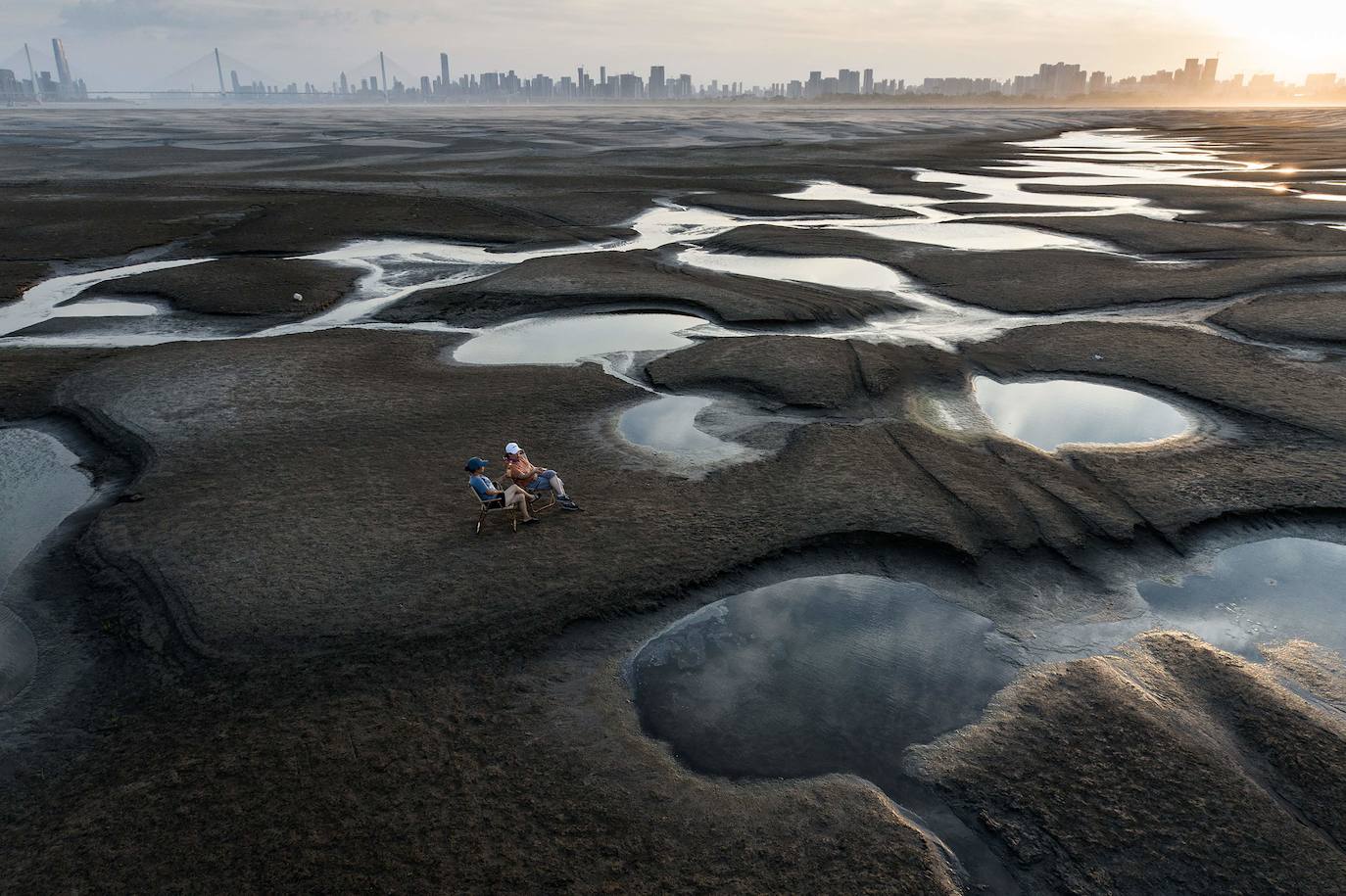 Esta foto tomada el 2 de septiembre de 2022 muestra a una pareja sentada en una sección del río Yangtze en Wuhan, que ha quedado seco. 