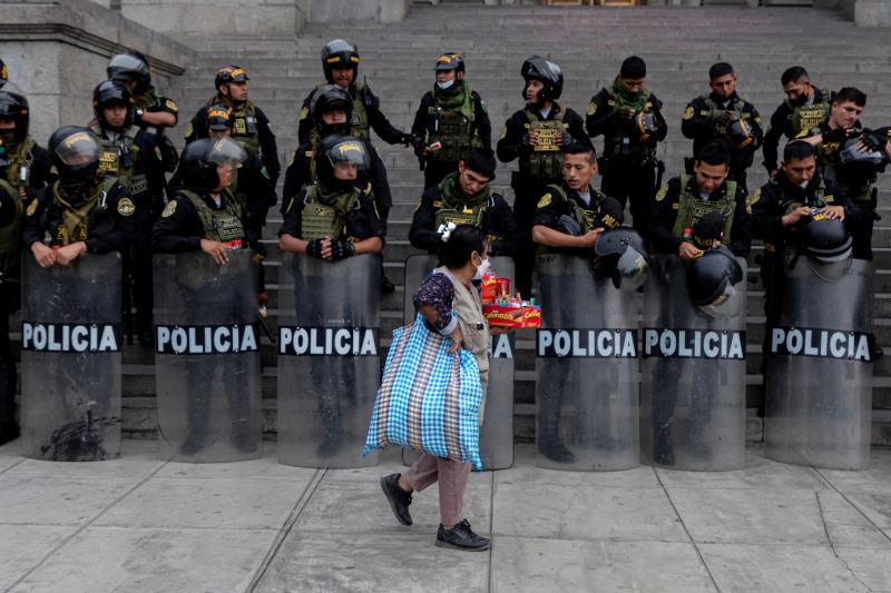 Una mujer cruza por delante de un cordón policial en la capital peruana