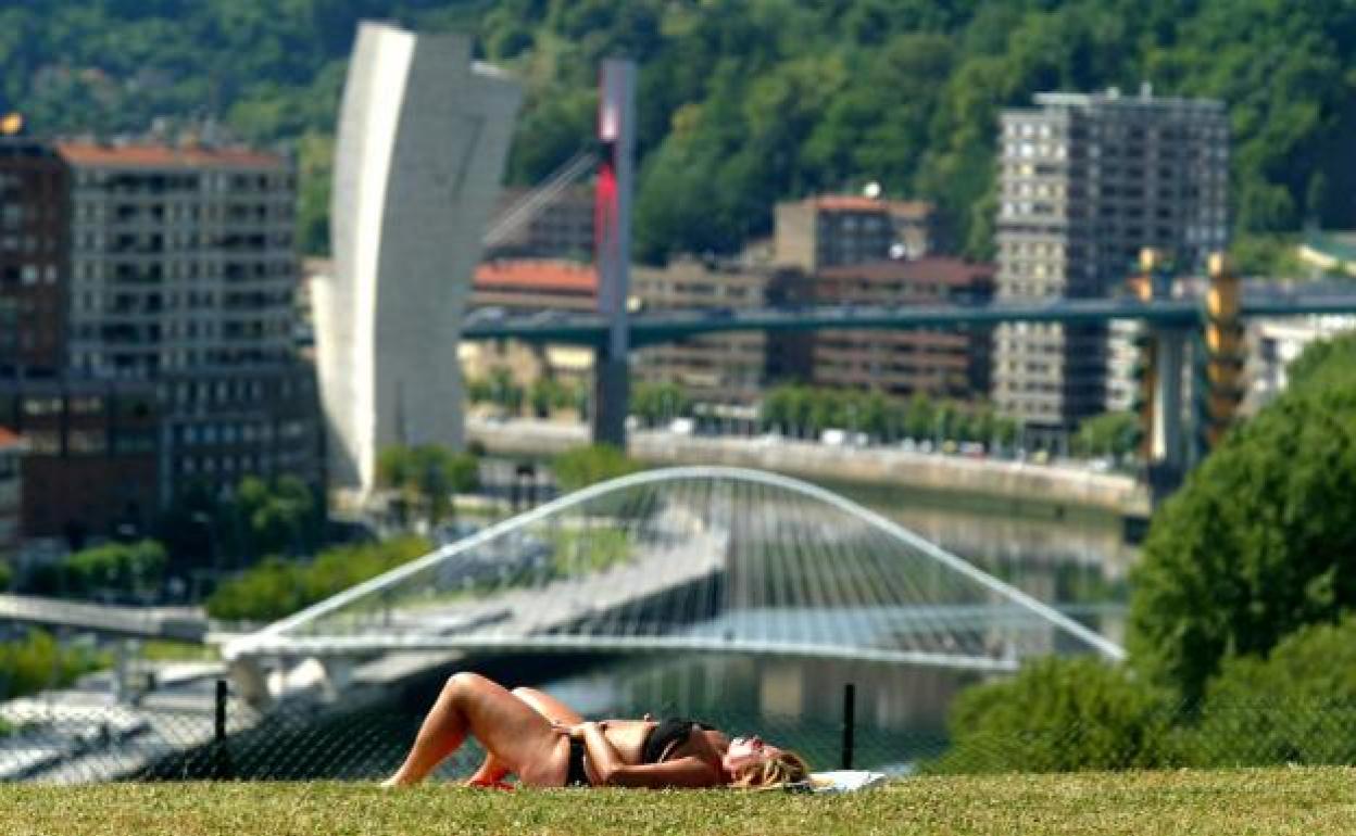 Una mujer toma el sol en un parque de Bilbao. 