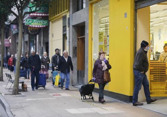 Varias personas, a la entrada de un supermercado asturiano.