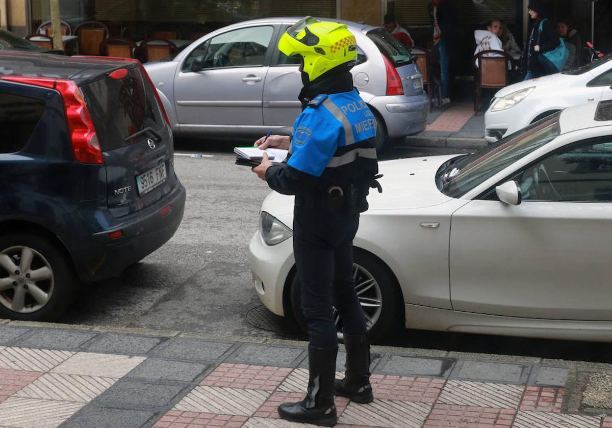 Un Policía Local de Mieres poniendo una multa a un coche.