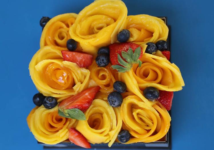 Imagen principal - Tarta de mango. La base es una crema con la que la chef pone de manifiesto su base de cocina francesa. Las flores las hace con dos tipos de mango, uno de ellos nipón, y decora con fresas y arándanos.