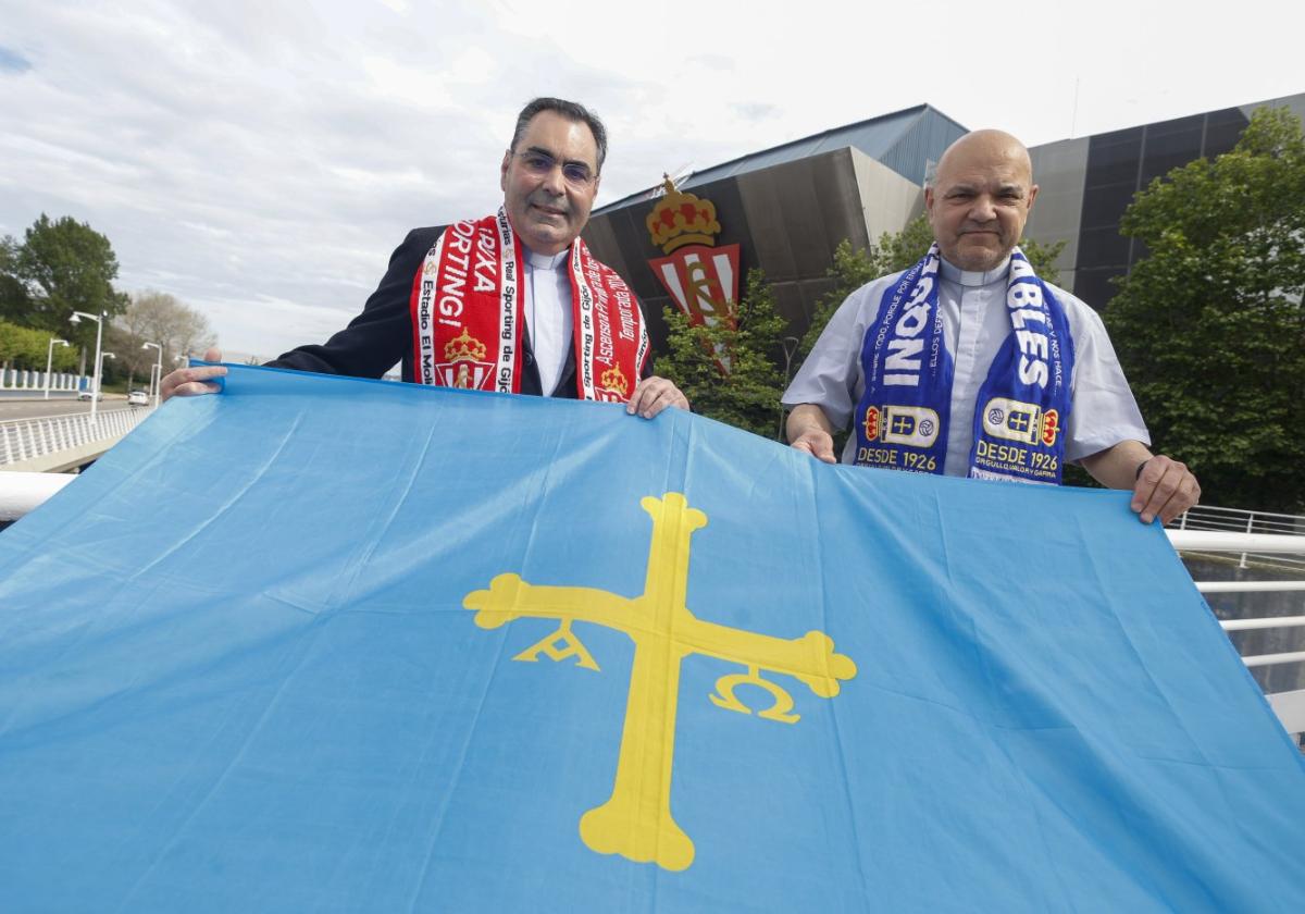 tLos capellanes del Sporting y del Real Oviedo, Andrés Fernández y Santiago Heras, con sus bufandas, sostienen una bandera de Asturias, con el estadio de El Molinón de fondo.