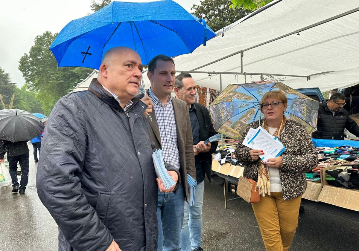 Adrián Pumares se resguarda de la lluvia bajo un paraguas en su visita de ayer al mercado de Sama de Langreo, junto al candidato local de Foro.