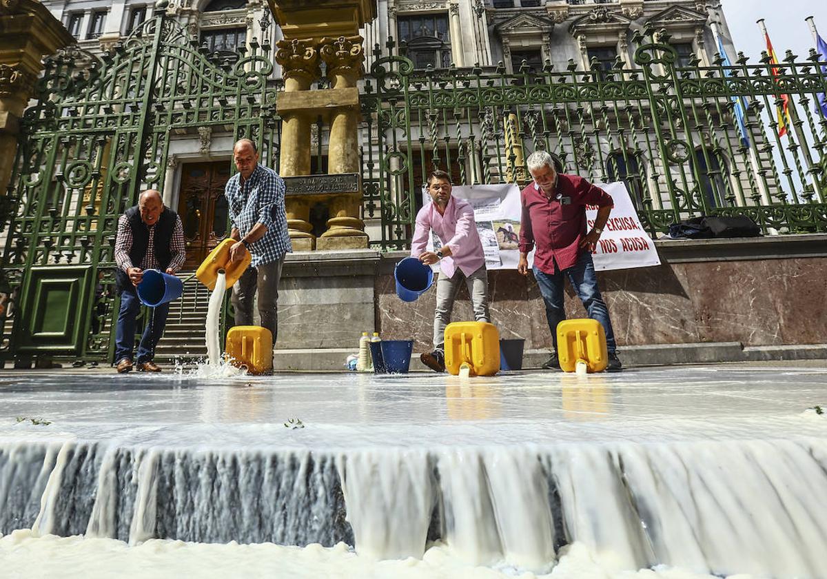 Representantes del sector ganadero derraman leche a la entrada de la Junta General del Principado como protesta por la propuesta de bajada del precio por litro producido.