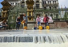 Representantes del sector ganadero derraman leche a la entrada de la Junta General del Principado, como protesta por la propuesta de bajada del precio por litro producido.