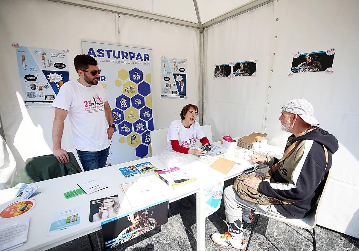 Juan Diego Álvarez y Susana Calvo atienden a un ciudadano en la carpa contra el tabaco.