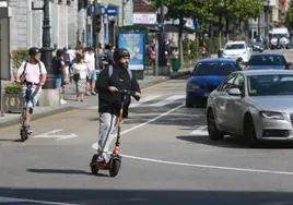 Dos hombres circulan con sus patinetes eléctricos por la calle Uría.