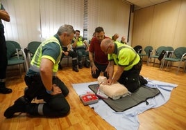 Dos agentes de tráfico simulan una maniobra de reanimación cardiopulmonar con un maniquí.