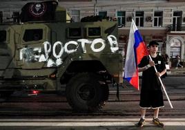 Un hombre sostiene la bandera nacional rusa frente a un vehículo militar del grupo Wagner en Rostov.