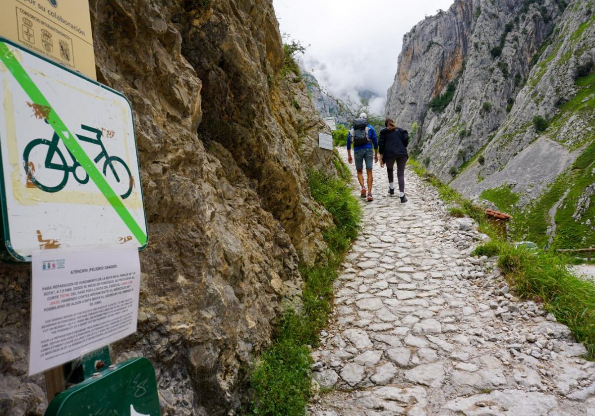 Senderistas al inicio de la Ruta del Cares, donde están colocados los carteles que advierten del corte.