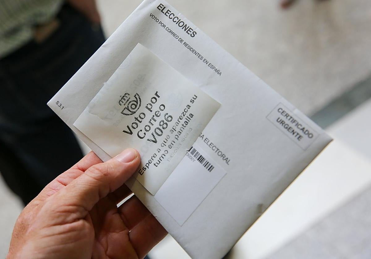 Una persona muestra sus papeletas antes de enviarla por correo en Gijón.