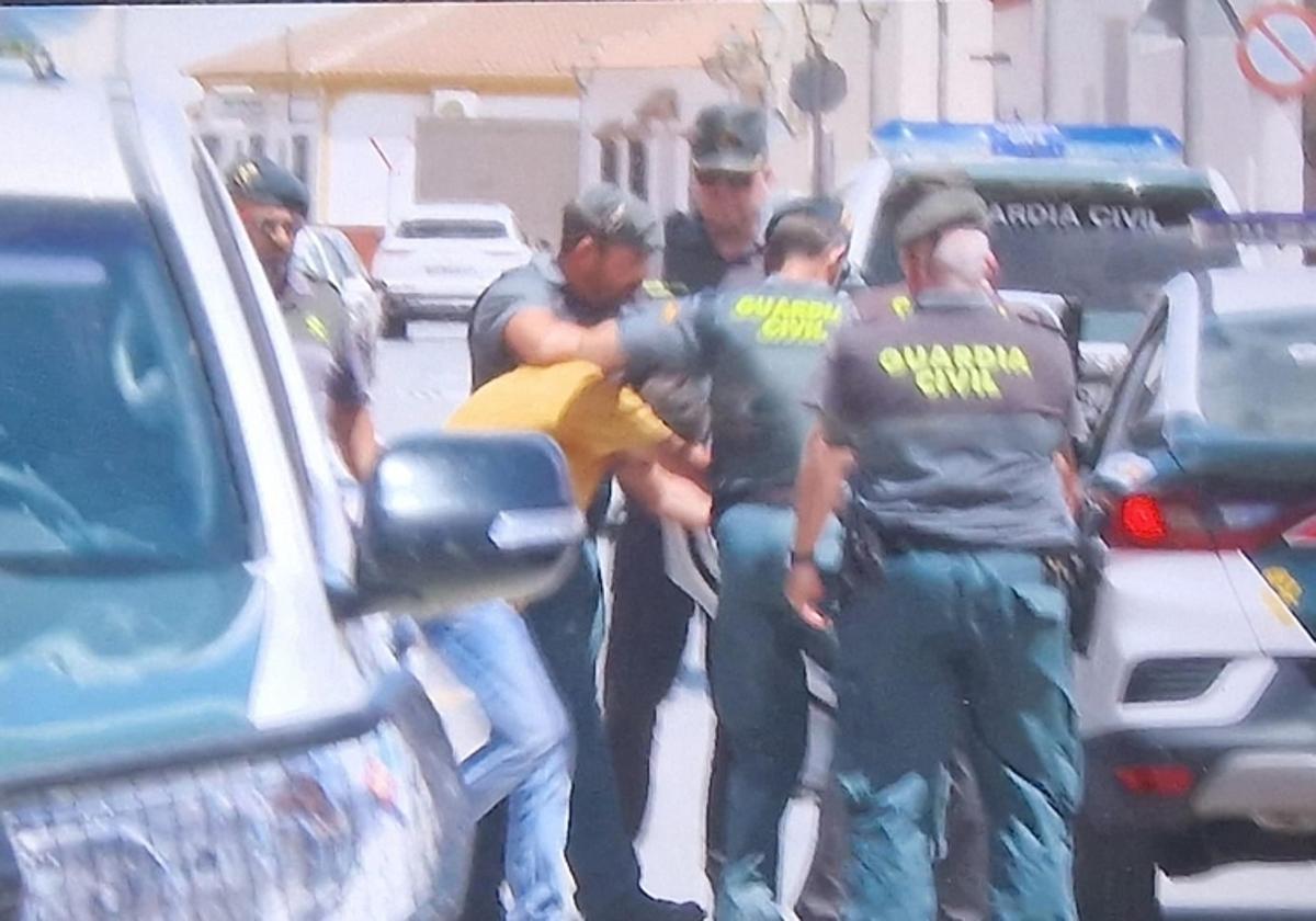 Guardias Civiles trasladan al detenido durante la reconstrucción realizada ayer en la vivienda.