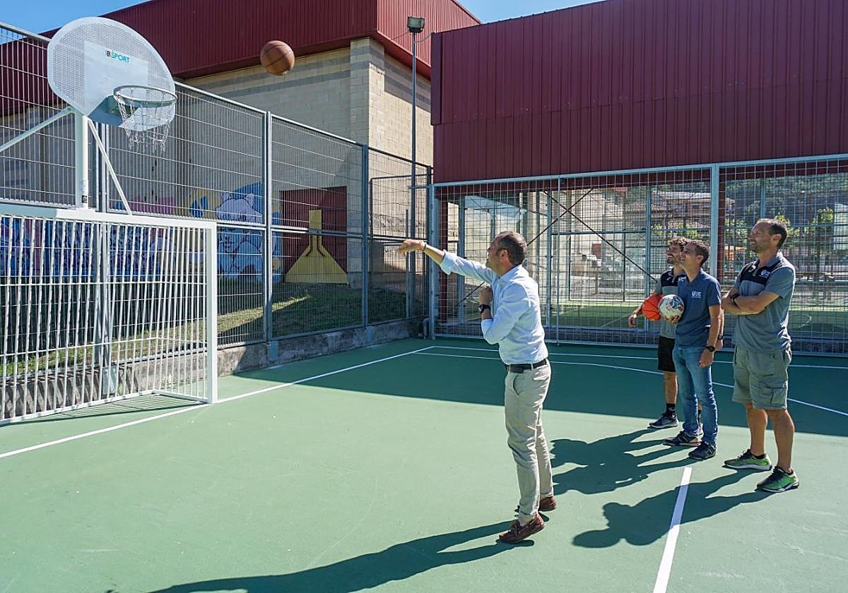 El alcalde, José Manuel González Castro, tira a canasta en la nueva pista polideportiva de Cangas de Onís ante los concejales Luis Miguel Solís y Agustín García y el director del Patronato Deportivo, José María Prieto.