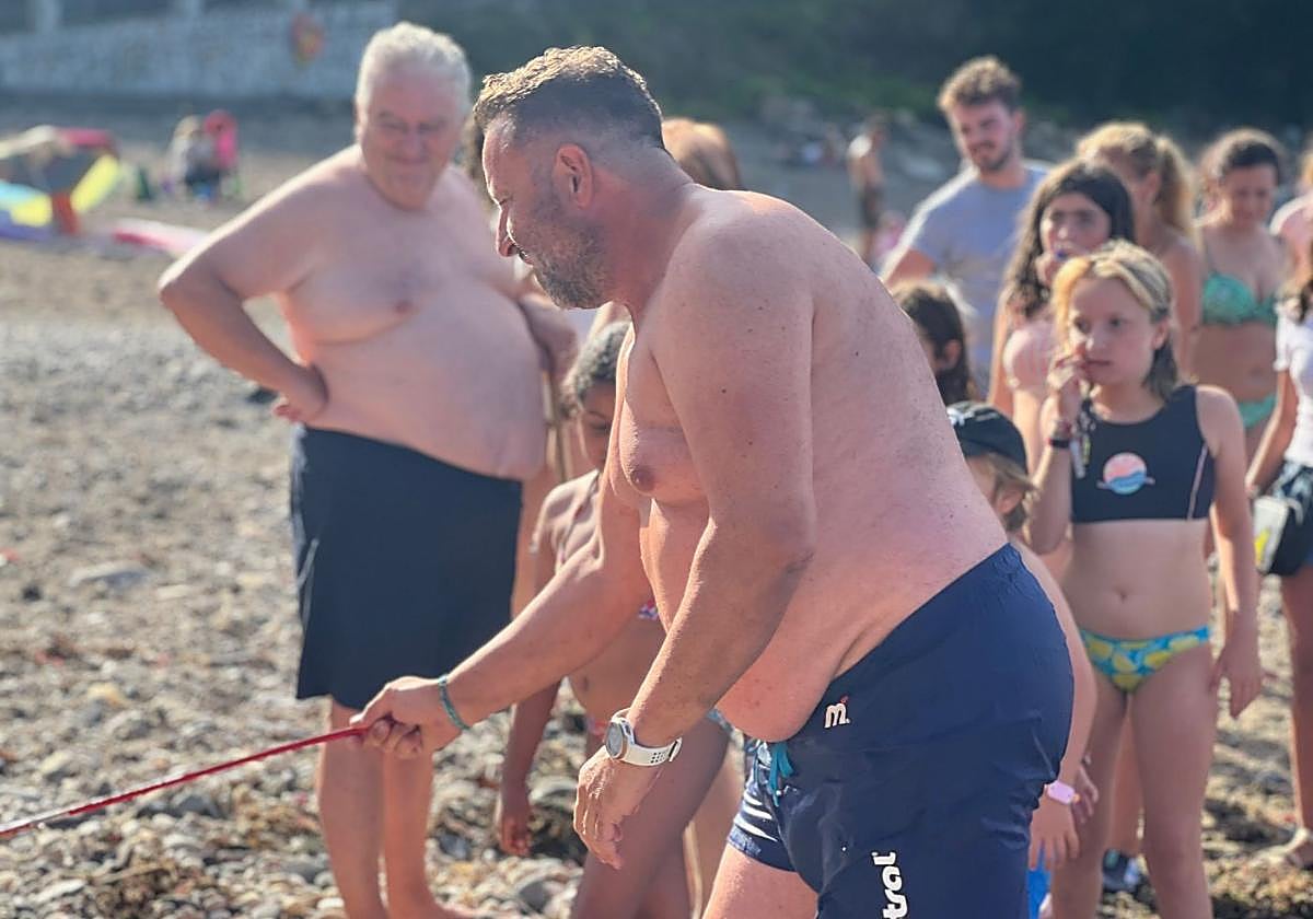 Un bañista saca a la carabela portuguesa del agua en Ribadesella.