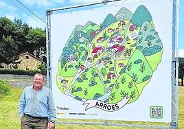 Ricardo Riera en Arroes junto a un cartel promocional de la parroquia premiada.