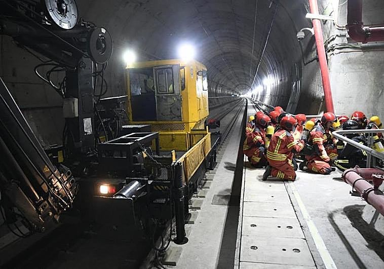 Los bomberos, junto a la dresina utilizada para llegar a la zona del siniestro, se preparan para acceder a la galería que conecta el tubo del túnel por el que se desplazaron con el otro tubo, en el que estaba el tren siniestrado.