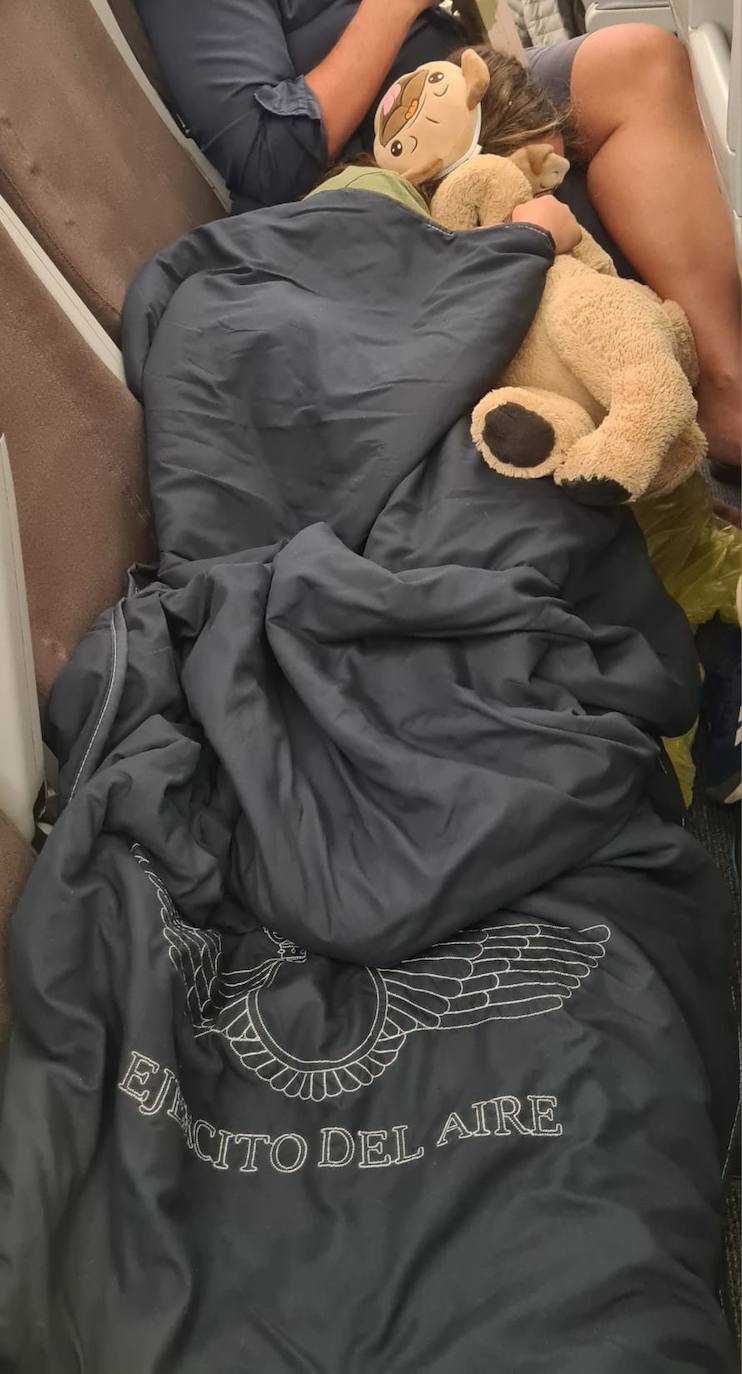 La hija de Joanna de Castro, tapada con la manta que les proporcionaron en el avión.