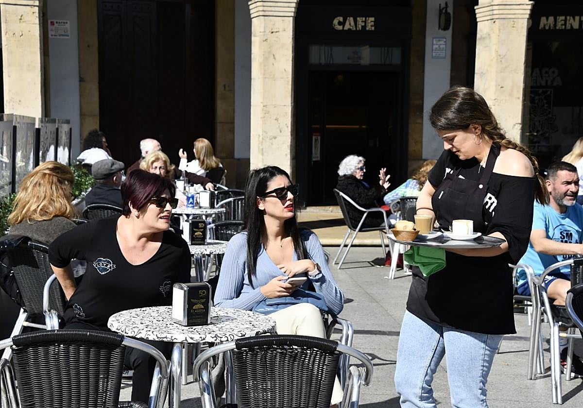 Una camarera atiende a unas clientes en una terraza de Avilés.