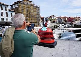 Un visitante toma una foto en el puente de Llanes, donde desde este año luce una 'menina' de Antonio Azzato.