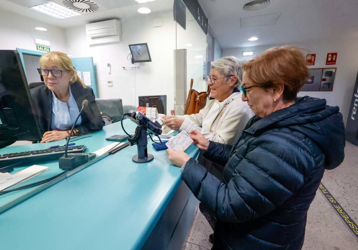 Dos viajeras compran billetes para viajar por la variante.