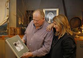 Familia.Padre e hija con una foto del fundador del llagar detrás y sosteniendo una imagen de la infancia de ella.