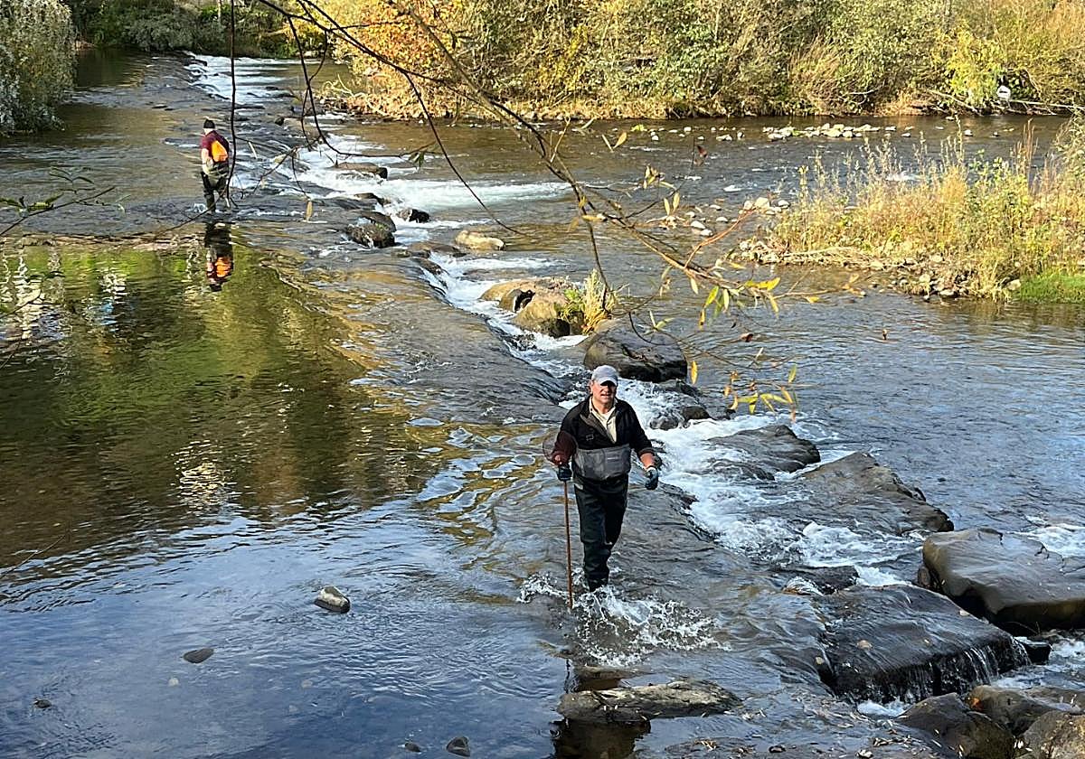 Pescadores recogiendo basura en el caudal.