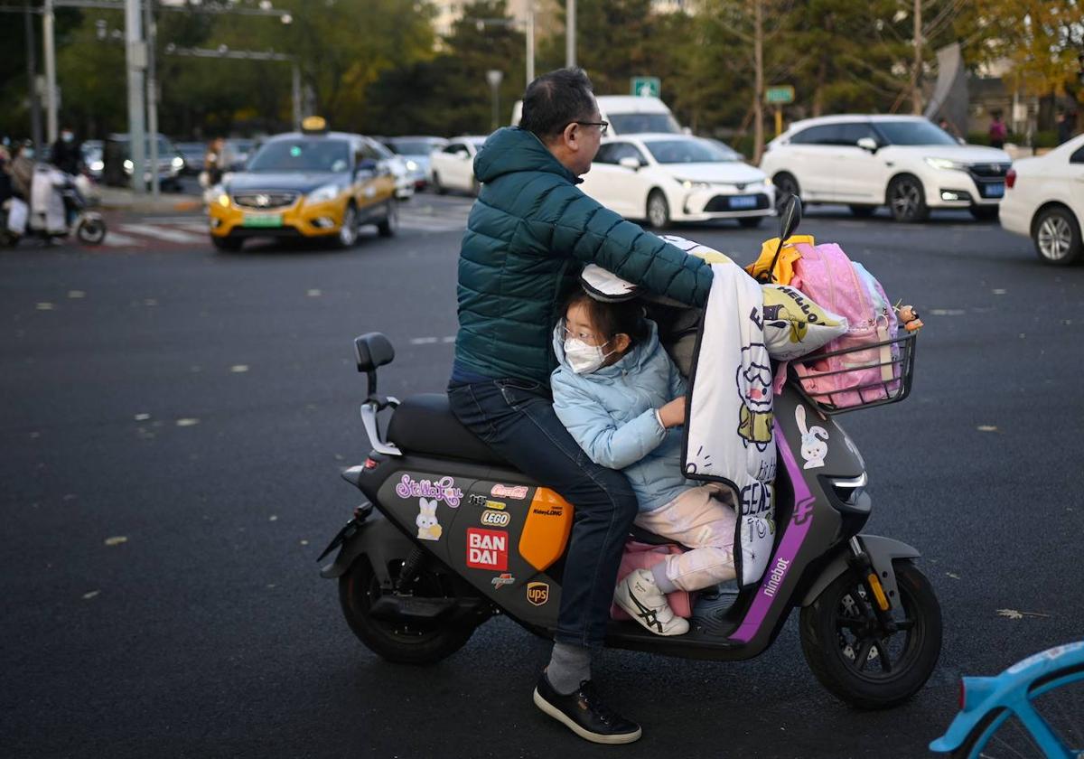 Una menor viaja con un adulto en una moto en Pekín.