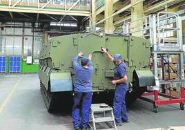 Dos trabajadores rematan uno de los blindados a cadenas que fabrica Santa Bárbara en Trubia.