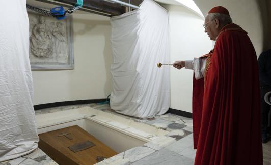 Un sacerdote observa el féretro del papa emérito Benedicto XVI en la cripta vaticana.