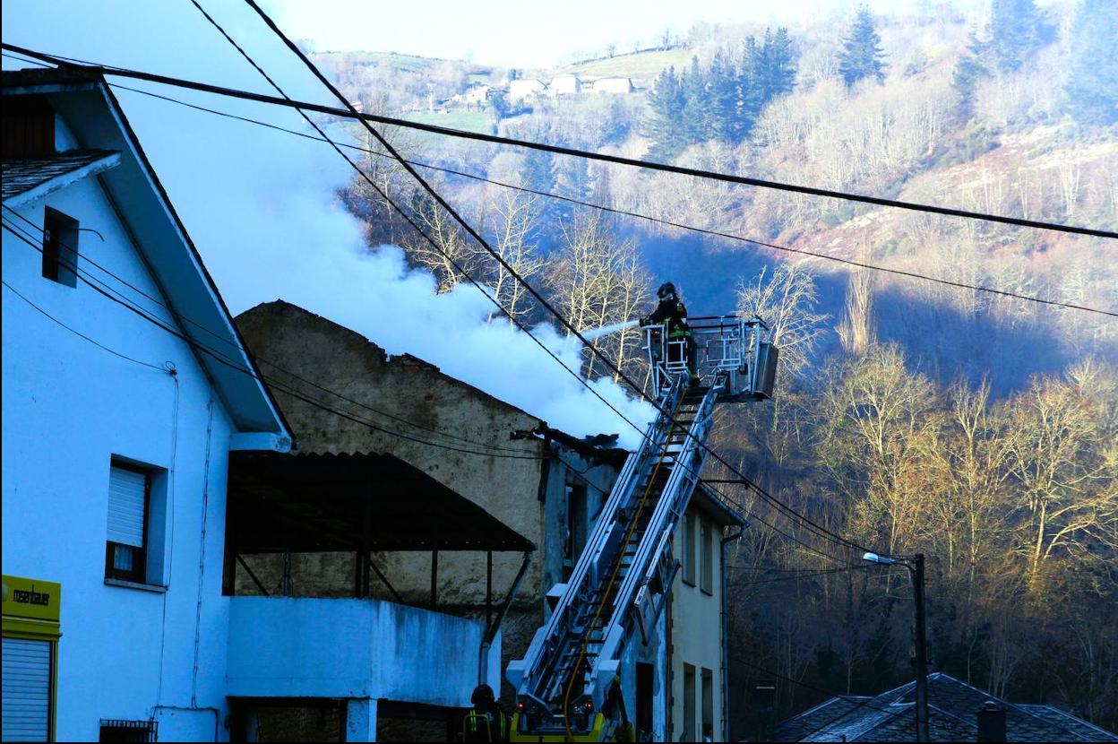 Sobre una grúa de gancho, un bombero termina de apagar ayer por la mañana las llamas del incendio en la vivienda. 