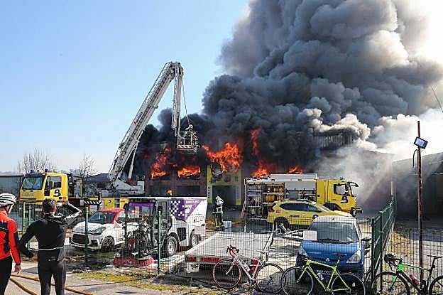 Efectivos de bomberos en las labores para sofocar el intenso fuego en la nave industrial afectada a la salida de El Berrón. 