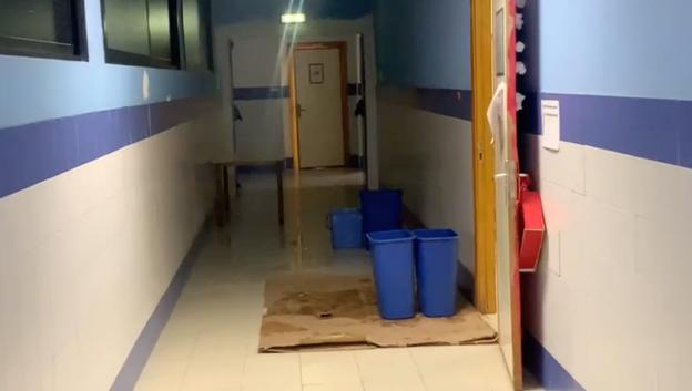 Uno de los pasillos del centro educativo con cubos para recoger el agua que cae del techo. 