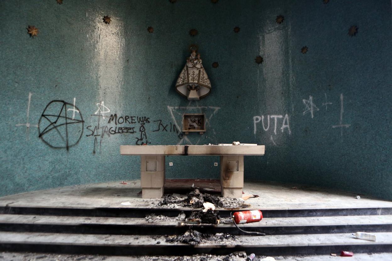 El altar con restos de un fuego y las paredes con grafitis. 