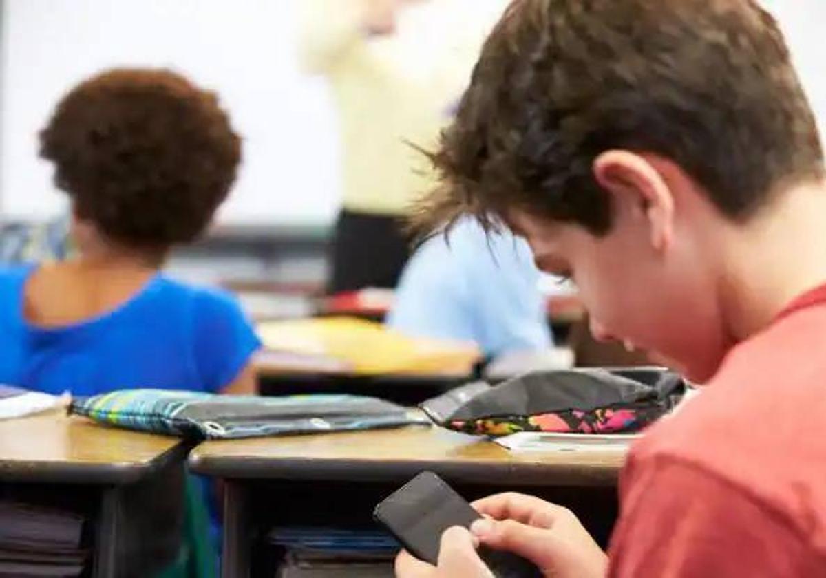 Un alumno utiliza su móvil durante una clase.