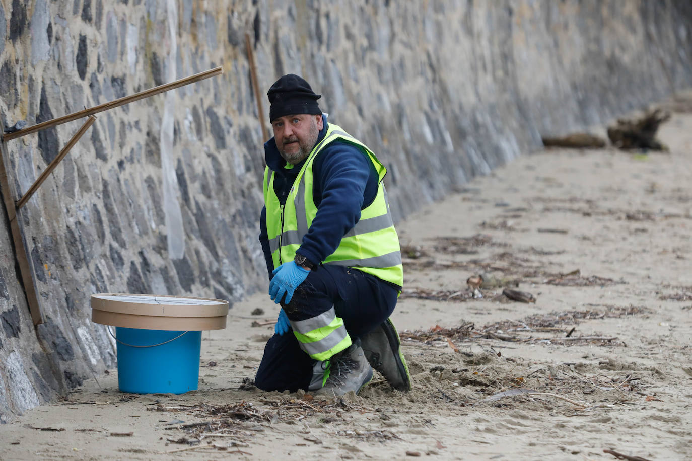 Operarios retiran los pellets o bolitas para fabricar plástico que aparecen en las playas de Asturias, tras la caída de un contenedor de un barco el pasado diciembre, esta mañana en la playa asturiana del Aguilar.
