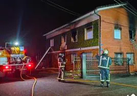 Los bomberos, durante las labores de extinción de un incendio en una vivienda en Nava.
