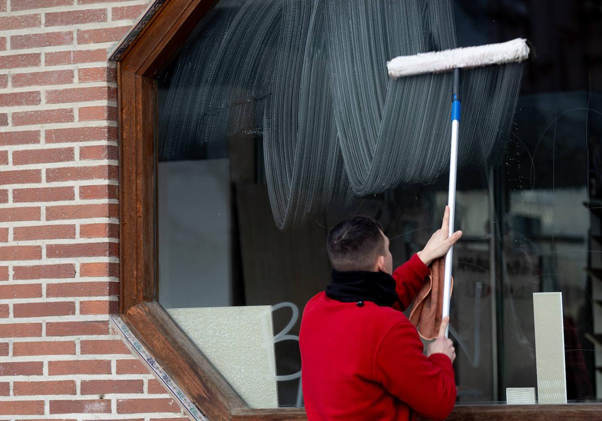 Un trabajador limpia el cristal de un establecimiento hostelero.