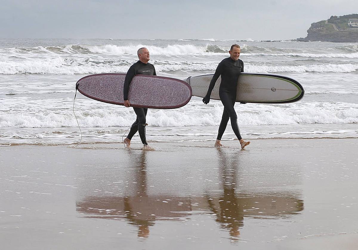 Dos surfistas salen del mar en la Playa de San Lorenzo, en Gijón.