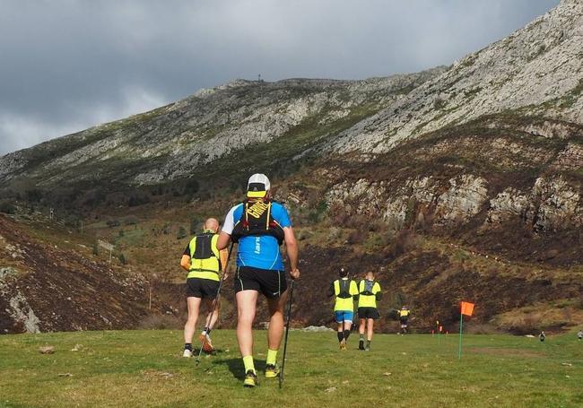 Corredores de otras ediciones mirando, al frente y alzada, la cruz de Pienzu, mitad de trayecto de una carrera de montaña con salida y meta en Arriondas