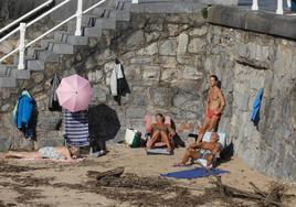 Un grupo de gijoneses disfruta de las altas temperaturas y el buen tiempo en la playa de San Lorenzo, en Gijón.