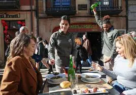 Gloría Díaz y Patricia Santos tomando el menú del Antroxu en la terraza del retaurante La Puerta de Cimadevilla.