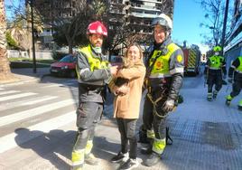 La dueña de 'Coco', con su gato y con los bomberos que rescataron al animal.