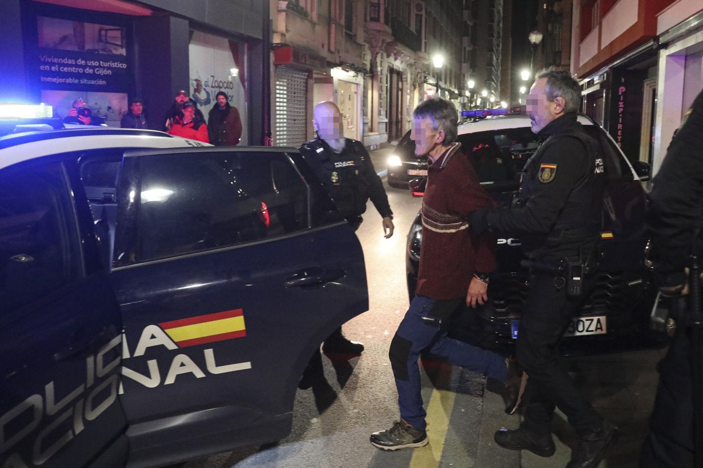 Uno de los detenidos es introducido en el coche policial.