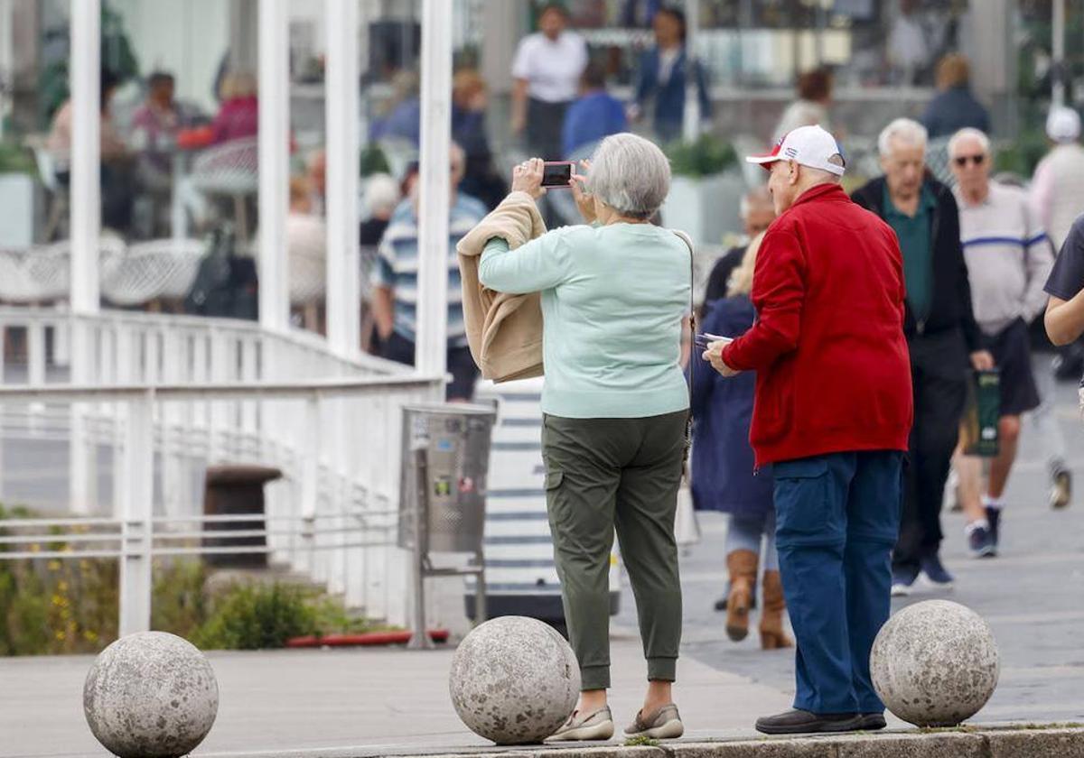 Una pareja de jubilados toma una fotografía en Gijón.