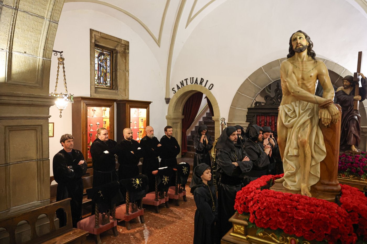 Varias personas, ante dos de los pasos de la Semana Santa candasina.