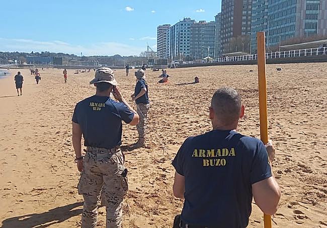 Buzos de la Armada hacen mediciones en la arena.